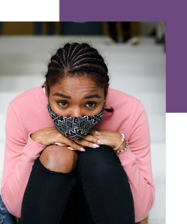 African American teen girl sits wearing a mask thinking about therapy to overcome thoughts of self-harm